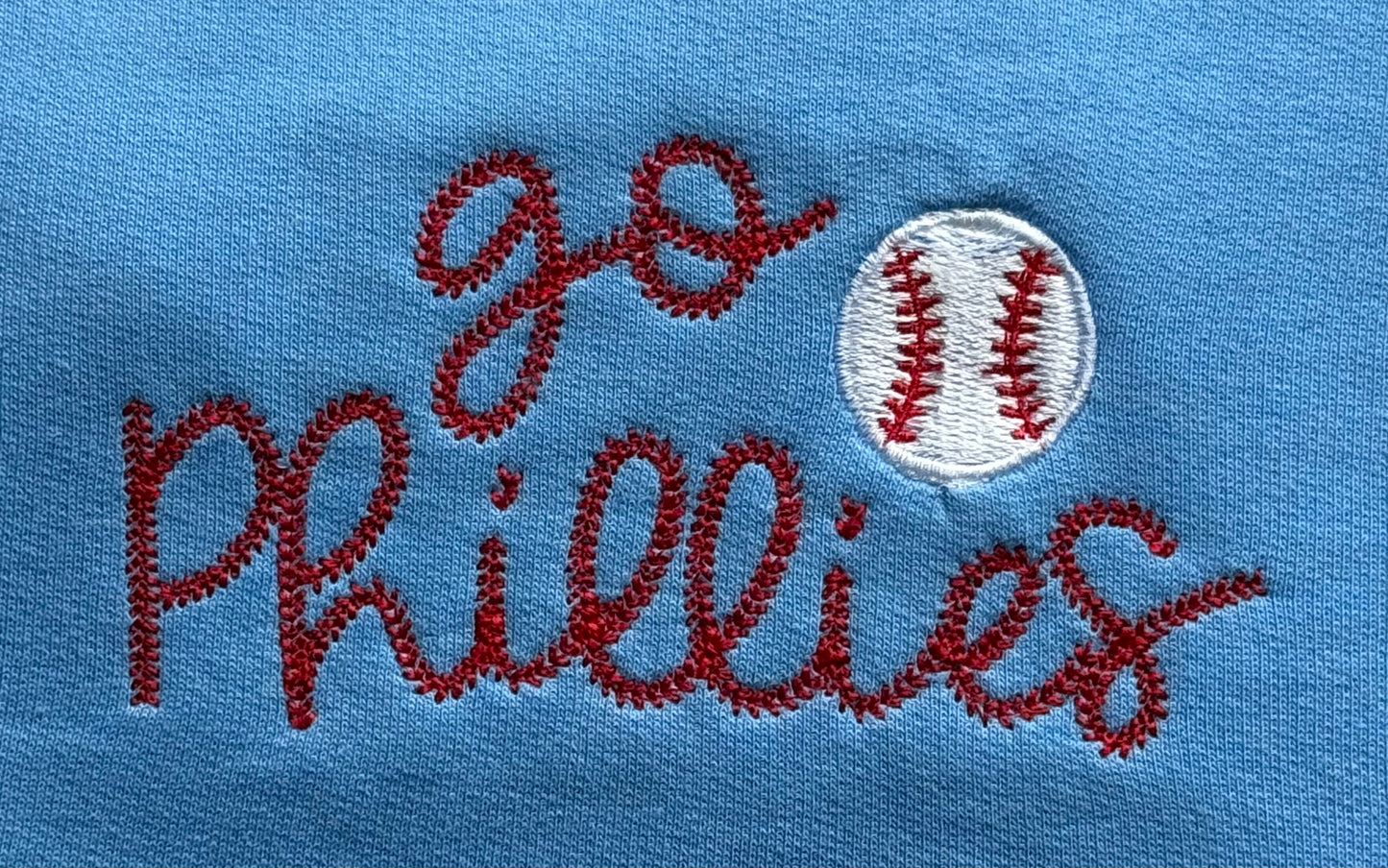 Embroidered text 'go Phillies' with a baseball on a blue background