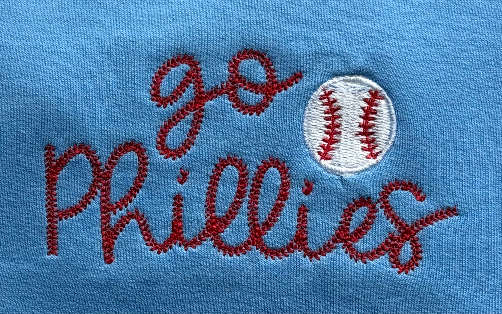 Embroidered text 'go Phillies' with a baseball on a blue background
