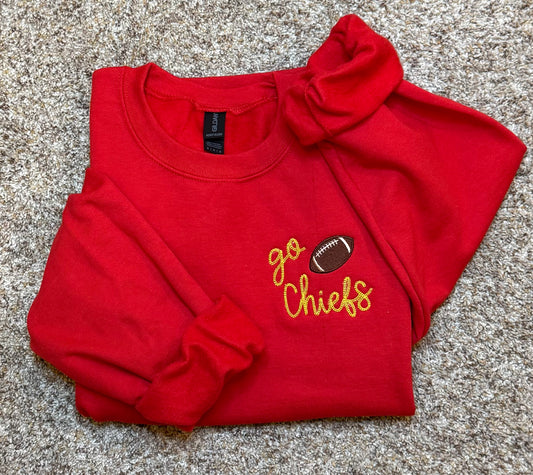 Folded red sweatshirt with 'go Chiefs' and football graphic on a textured surface
